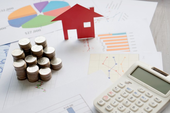 With House Model And Stack Of Coins On Desk