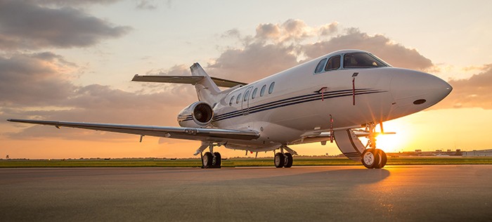 Corporate business jet setting on ramp with door open and sun setting in the background.